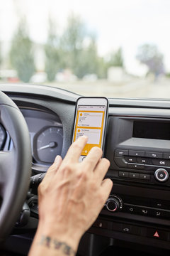 Close-up of man using delivery application in car.