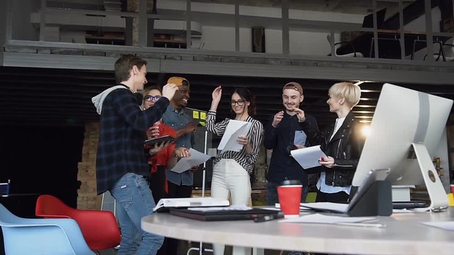 Successful group of young stylish man and woman giving five to each other.