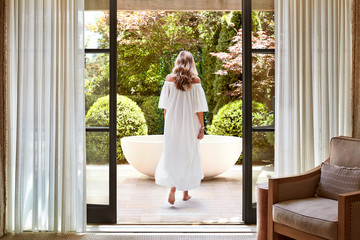 Woman walking towards outdoor bathtub at luxury resort