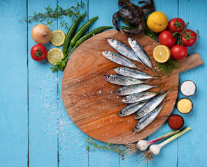 Horse mackerel with vegetables on blue wooden background