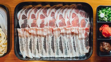 Premium Rare Slices Kurobuta pork with high-marbled texture on black rectangle plate served for Sukiyaki and Shabu.