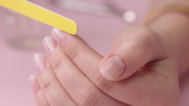 closeup woman file her nails use yellow emery board