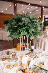 close-up view of delicious dishes, bottles with drinks and floral decor on table at wedding reception