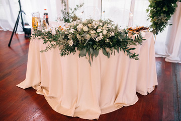 beautiful flowers with green leaves on served table with pink tablecloth at wedding reception