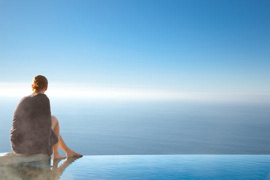 Woman sitting on edge of infinity pool