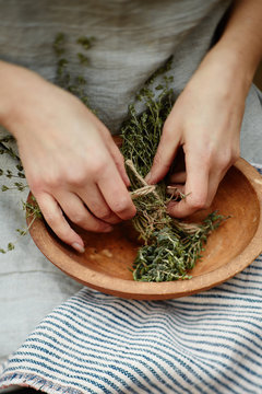 Woman tying fresh Thyme with twine in a bowl