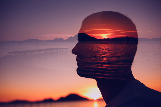 Silhouette of a young man in the background of the sunrise over the sea. Double exposure.