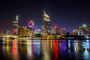Fototapeta na wymiar Ho Chi Minh City, Vietnam - May 7, 2019 : Riverside City at nightclouds in the sky at end of day brighter coal sparkling skyscrapers along beautiful river in Ho Chi Minh City, Vietnam - Image