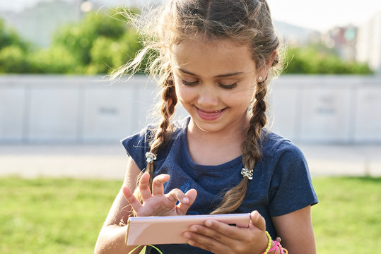 Little girl using smartphone at park.