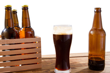 glass of beer and bottles with no logo on wooden table isolated copy space, glass bottle