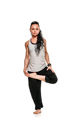 Fototapeta premium Portrait of young woman standing on one leg while practicing yoga