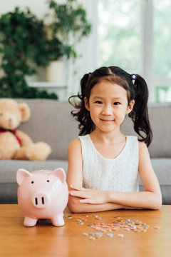 Chinese girl putting coins into piggy bank