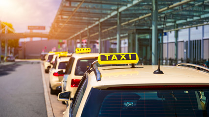 Taxi cabs waiting for passengers. Yellow taxi sign on cab cars. Taxi cars waiting arrival passengers in front of Airport Gate. Taxis stand on Airport Terminal waiting for passengers.