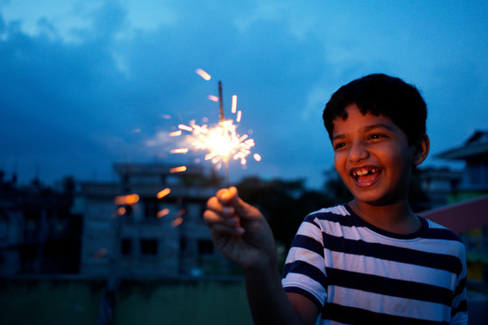 Happy young boy with sparkler at dusk