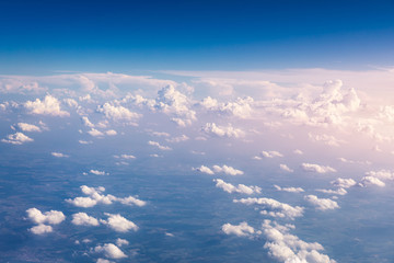 Fototapeta na wymiar Amazing clouds and the sky as seen through the window of an aircraft. Clouds, sun, sky as seen through window of an aircraft. Bright blue sky with clouds and sunlight seen through an airplane window.