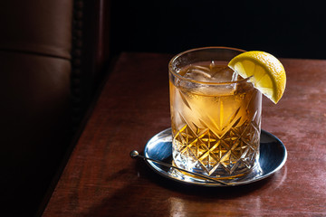 Whiskey Soda or Scotch and Water Mixed Drink with Ice and Lemon in Dark Luxurious Bar with Copy Space