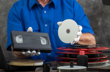 hand photographer holding VHS tape and DVD disc for conversion