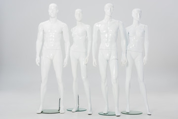 white plastic mannequins in row on grey - obrazy, fototapety, plakaty