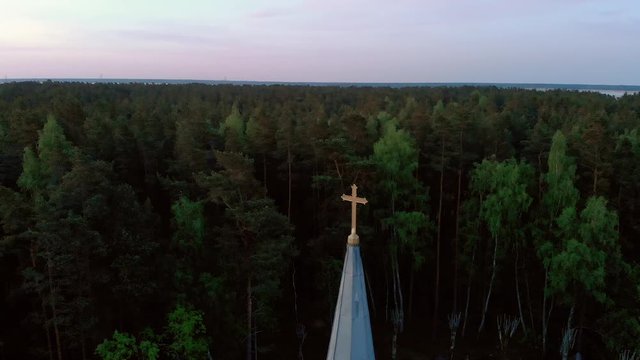 Aerial top view circle around cross of beautiful church in Jurmala during Golden Hour sunset - Sala Sv. Janis ev. lutheran