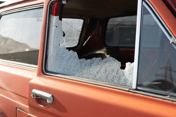 Car window smashed by a thief. Car broken window. Broken right side window of a car parked on the street. Theft from the car. A criminal incident. The car after the accident