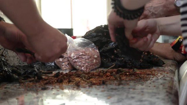Front View close-up. Women cleaning and removing seeds from chile. Women making Mole in Puebla Mexico. North America.  Cooking Traditional recipe