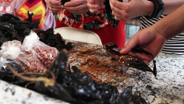 Front View close-up. Women cleaning and removing seeds from chile. Women making Mole in Puebla Mexico. North America.  Cooking Traditional recipe