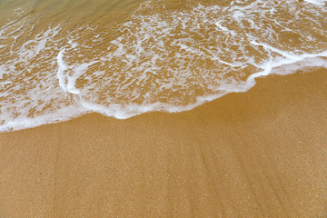 Blue ocean wave on sandy beach. Soft wave of blue ocean on sandy beach. Background. Top view of Beautiful beach with tranquil wave, sea and ocean background, summer vacation concept.
