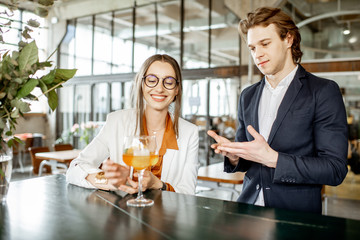 Businessman flirting with young woman sitting with cocktail at the bar