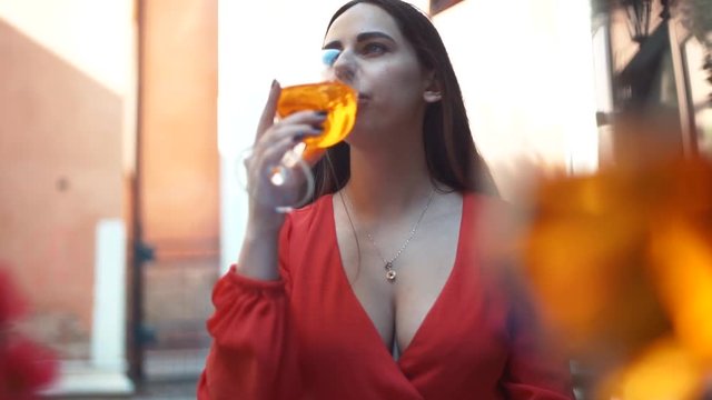 Girl drinks a cocktail spritz aperol in a cold glass in a warm Sunny day in a street cafe