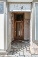 Alter kaputter Eingangsbereich einer Haustüre mit Glaswänden und Glasüberdachung, Deutschland
