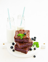 Chocolate brownies with blueberries and cream filling. Dark background.