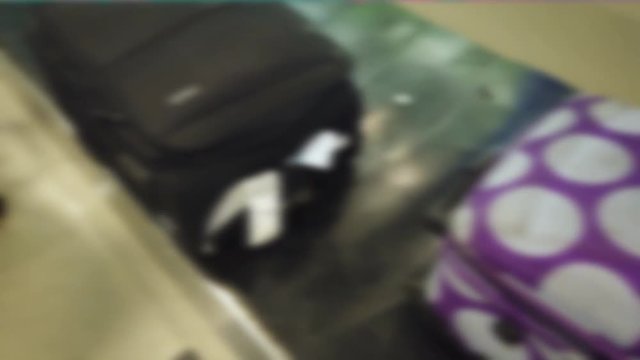 Blurred, defocused footage of suitcase, luggage moving on conveyor belt and passengers waiting in the airport. Blur, blurry, defocus of people wheeled suitcase on luggage belt at the airport terminal