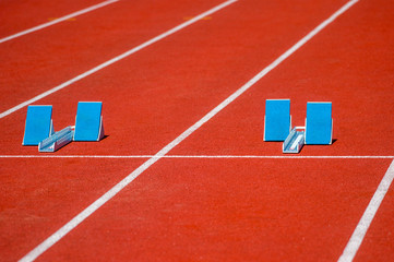 Athletic start block on dark red tartan track