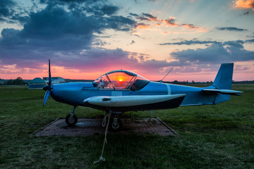 Fototapeta na wymiar A small sports airplane parked at the airfield at scenic sunset