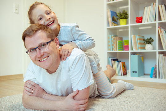 Young happy father having fun with  cute daughter at home