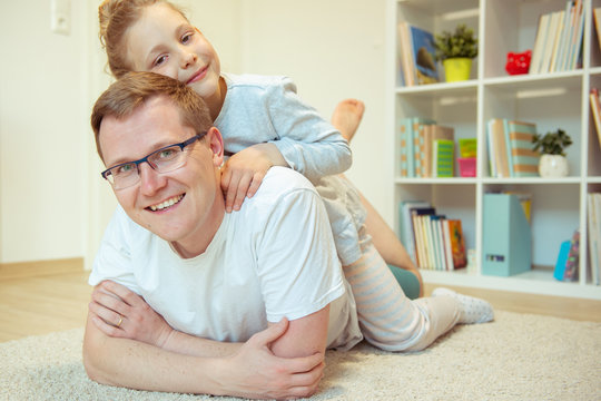 Young happy father reading book with  cute daughter at home