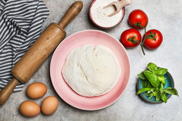 Bollo de masa crudo con huevos, albahaca, tomates sobre una mesa gris. Vista superior y de cerca. Concepto: Composición, receta, preparación - Powered by Adobe