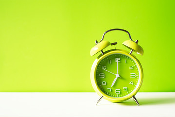 Green alarm clock on green pastel  background with coppy space