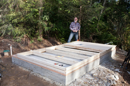 Man takes a break from building a shed wall