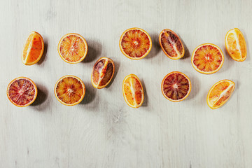 Group of fresh organic Sicilian blood oranges sliced and whole in row over white wooden background....