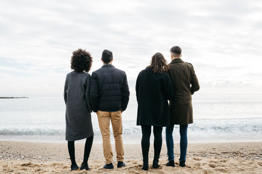 Two couples standing on the beach.