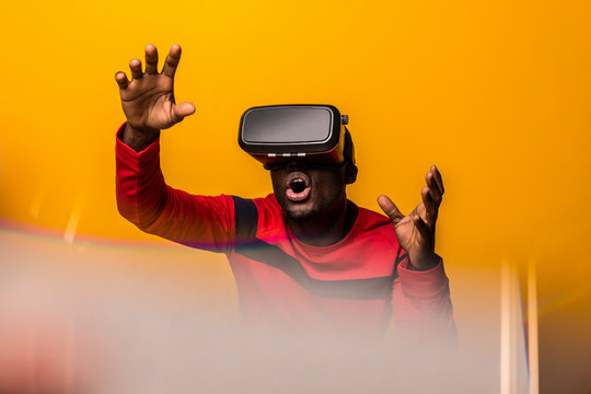 Black happy man using VR glasses over a yellow background