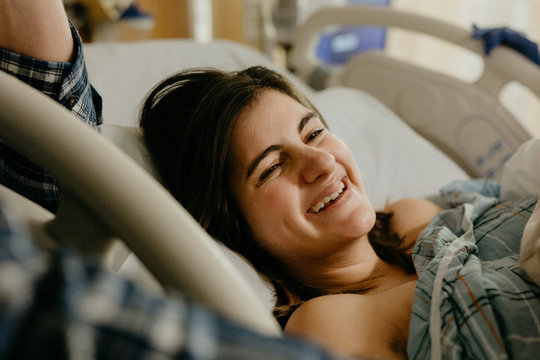 A Young Woman Smiling While Giving Birth At The Hospital