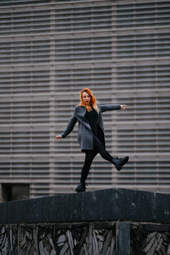 woman playing/dancing in front of a functional architecture building