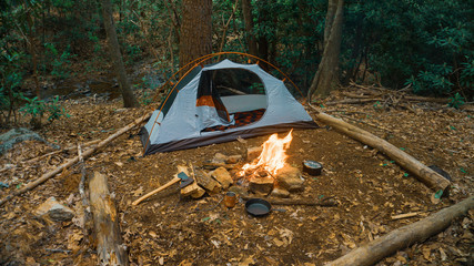 Camping tent in the Blue Ridge Mountains in Asheville, North Carolina. Outdoor lifestyle with axe, cast iron skillet, flannel blanket. Rustic Bushcraft Campsite. Survival shelter in the wilderness. 