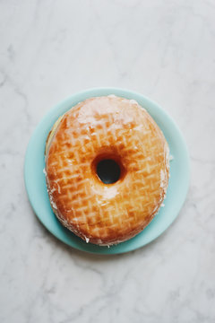 Single glazed doughnut on a turquoise plate
