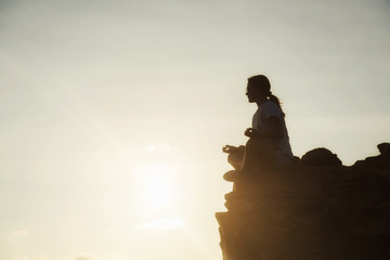 Naklejka premium Yoga at mountain summit during sunset