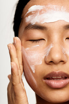 Young natural asian woman portrait applying moisturiser.