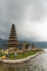 Obraz premium Bali, Indonesia - February 25, 2019: Ulun Danu Beratan Temple complex in Bedoegoel. Tengahing Segara temple is pagoda of eleven levels with adjacent shrine, all on island under rainy cloudscape. Green