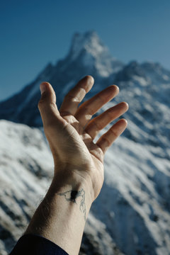 Anonymous male tattooed hand in front of mountains background